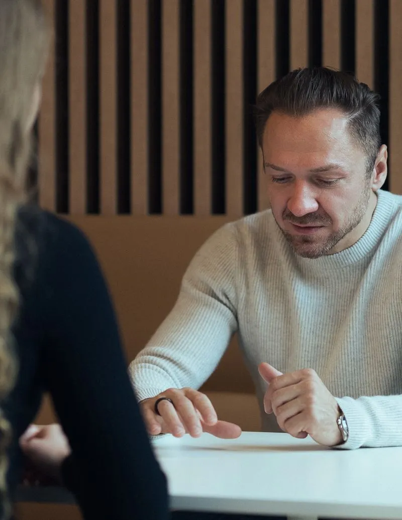 Person in hellem Pullover an einem Tisch sitzend