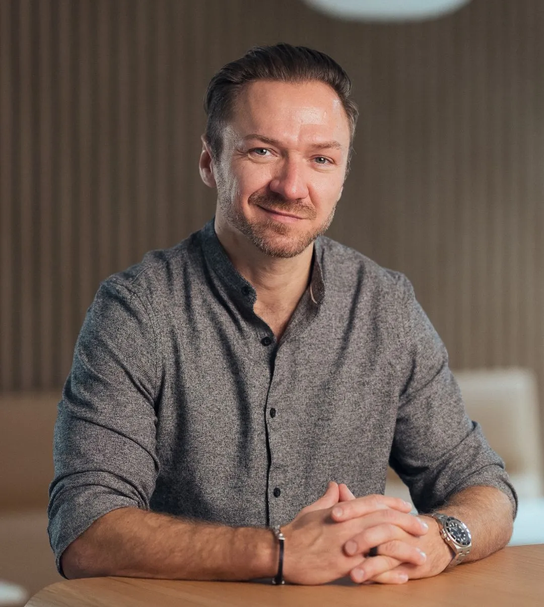 Coach Gregor Wojtowicz aus Köln in grauem Hemd vor Holzlamellenwand